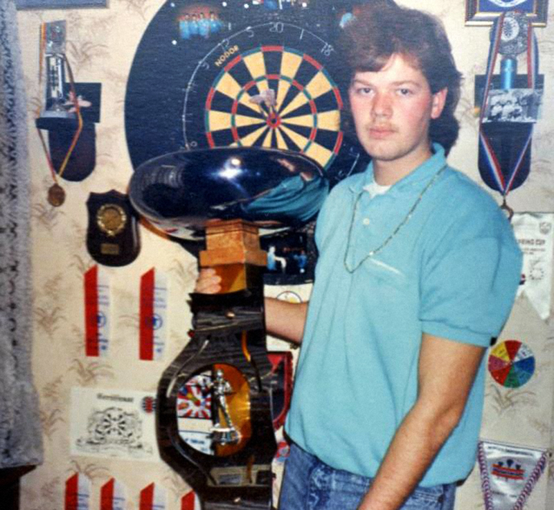 Een jonge Raymond van Barneveld met een darts trofee
